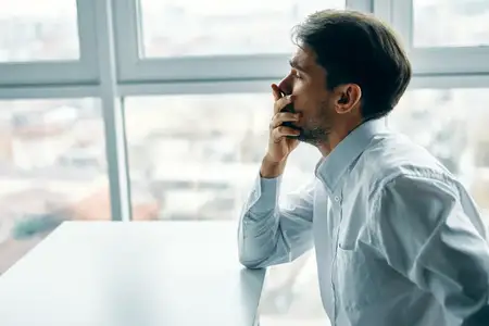 Мужчина сидит за офисным столом, испытывая эмоции депрессии и стресса