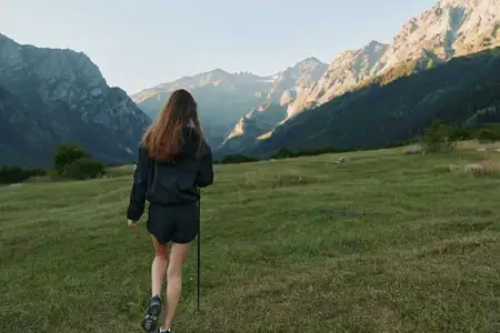 Невидимый турист на отдаленном лугу смотрит на далекие вершины