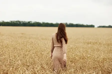 Женщина-фермер, озабоченная созреванием колосьев пшеницы в начале лета в солнечный день