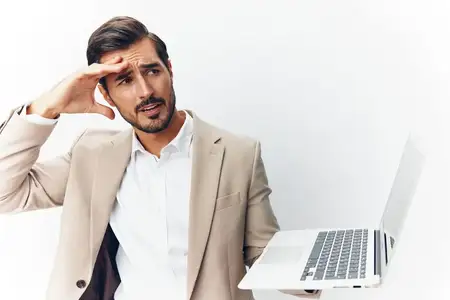 Улыбающийся мужчина в деловом костюме работает за ноутбуком в офисе