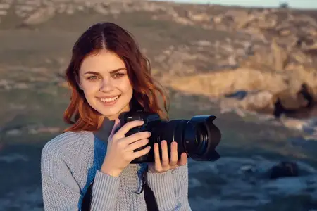 Женщина-туристка с фотоаппаратом наслаждается природой, свежим воздухом и отпуском во время путешествия