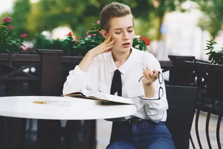 Коротко стриженная женщина отдыхает на улице, весело прогуливаясь по городу, что связано с образованием