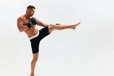 Спортивный мужчина, культурист, позирует в боксёрских перчатках с обнажённым торсом и рельефным прессом на полный рост на размытом фоне