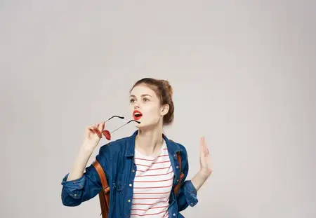 Улыбающаяся молодая женщина в модной одежде с рюкзаком, студентка колледжа