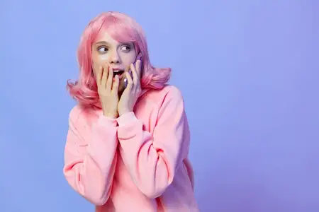 Молодая женщина пользуется смартфоном и улыбается на фиолетовом фоне