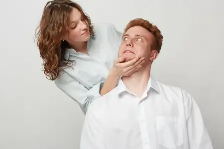 Молодая женщина нежно касается лица мужчины, в то время как он с удивлённым выражением смотрит вверх
