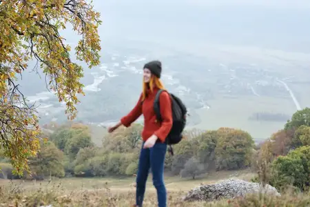 Женщина-туристка путешествует в горах среди осенних деревьев, отдых