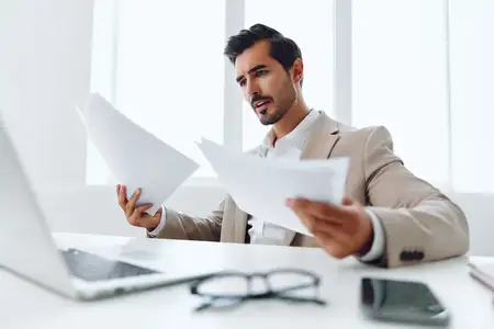 Уверенный руководитель в деловом костюме планирует работу в офисе, общается с коллегами и держит в руках документы