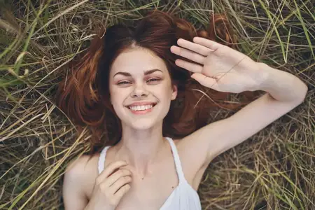 Жизнерадостная женщина лежит на траве в поле, отдыхая на природе