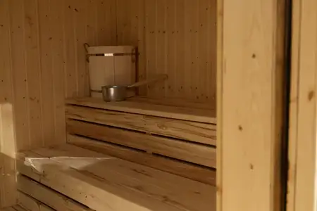 Умиротворяющая комната сауны с деревянными скамьями, панелями и металлическим ведром