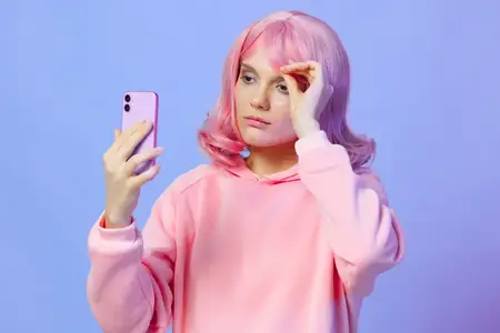 Женщина делает селфи, улыбается и позирует на фиолетовом фоне