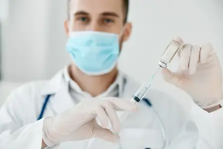 Врач со шприцем в руке, вакцина от коронавируса, медицинский халат и маска для лица