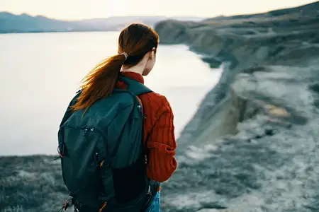 Женщина на отдыхе в горах на фоне заката и моря