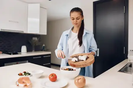 Привлекательная молодая женщина готовит здоровую пищу на красивой кухне