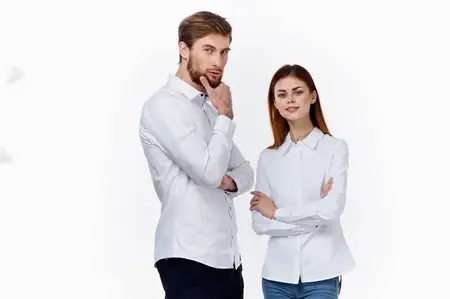 Сотрудники на работе: мужчина и женщина в одинаковых рубашках на светлом фоне стоят друг напротив друга
