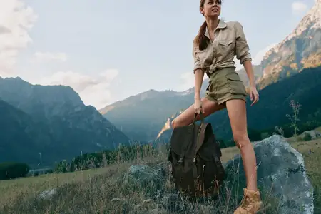 На ней хаки-рубашка, шорты и прочные ботинки, пока солнечный свет заливает долину