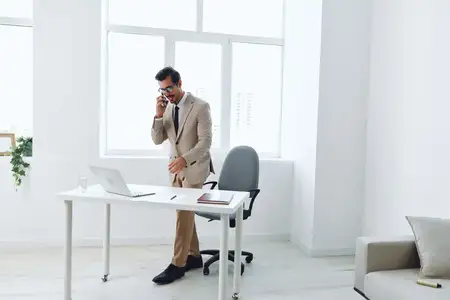 Современный мужчина в деловом костюме сидит за столом в офисе, работая за компьютером