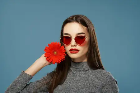 Красивый портрет брюнетки с красным цветком у лица, крупный план