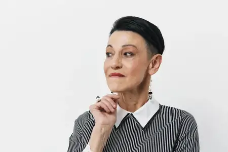 Портрет стильной женщины с короткой стрижкой в черно-белой полосатой рубашке, позирующей для камеры