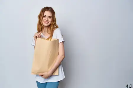 Женщина в белой футболке с пакетом продуктов на светлом фоне