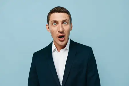 Счастливый молодой мужчина европеоидной внешности в повседневной одежде на белом фоне