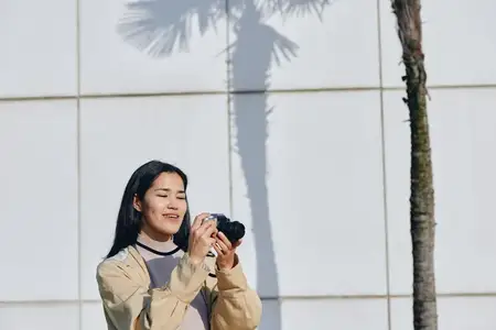 Фотография, камера, женщина на улице, естественный снимок, ладонь, стена, дневной свет, фокус, креативный кадр, повседневная одежда, городская обстановка, безмятежное настроение, естественное…