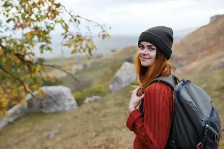 Женщина-туристка с рюкзаком в горах, осеннее путешествие