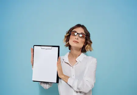 Папка с белым листом бумаги в женских руках на синем фоне, на лице очки