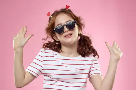 Весёлая девушка с косичками, в солнцезащитных очках и полосатой футболке, образ жизни, розовый фон