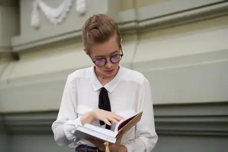 Коротко стриженная женщина с книгой в руках на открытом воздухе читает и общается