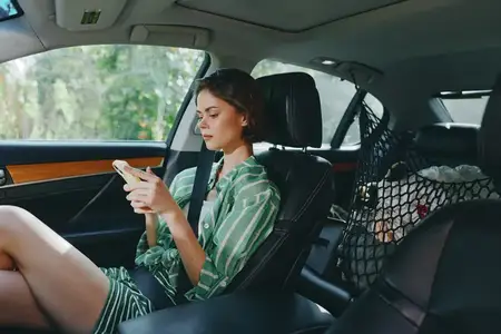 Интимная сцена в интерьере с расслабленной атмосферой, вид с пассажирского сиденья, тонкие текстуры, тихий момент во время путешествия, повседневное использование техники