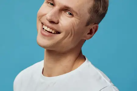 Крупный план портрета улыбающегося мужчины с короткими каштановыми волосами и белой футболкой
