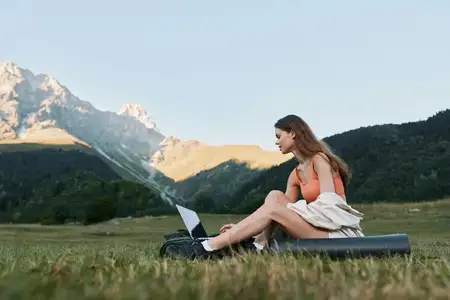 Сосредоточенный человек работает удаленно в живописной обстановке на открытом воздухе, сочетая природу и технологии в мирной сцене концентрации и личной продуктивности