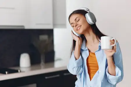 Женщина наслаждается музыкой и кофе в стильном интерьере кухни с современным дизайном и уютной атмосферой