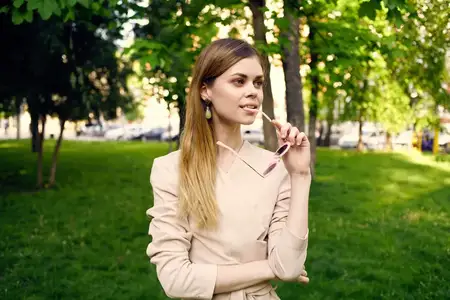 Симпатичная женщина в солнцезащитных очках, кадр обрезан, на переднем плане зелёная трава и свежий воздух