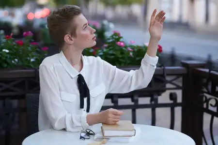 Девушка в летнем кафе читает, прогуливаясь на свежем воздухе, что символизирует образование