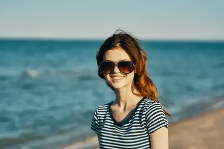 Красивая женщина-модель в солнцезащитных очках у моря в горах