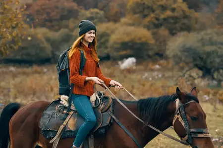 Женщина-туристка верхом на лошади в горах