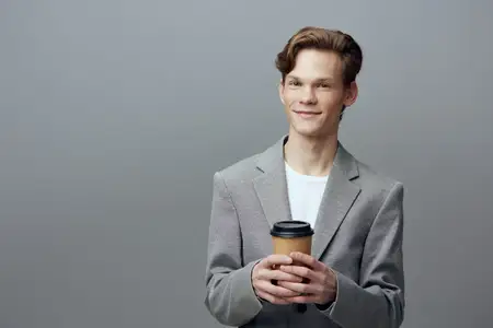 Молодой бизнесмен улыбается, глядя на смартфон; мужчина в деловом стиле кэжуал; технологии и коммуникация