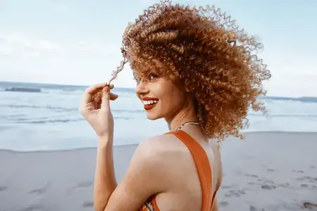 Улыбающаяся женщина с рюкзаком наслаждается счастливым отпуском на пляже