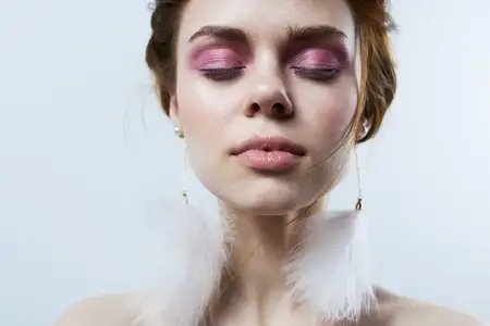 Женщина с закрытыми глазами, обнаженными плечами, ярким макияжем