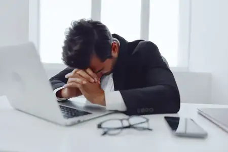 Мужчина на работе испытывает стресс, сидя в помещении