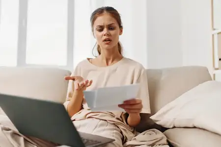 Улыбающаяся женщина работает за ноутбуком в уютном домашнем офисе