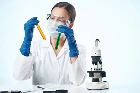 Женщина-лаборант в желтых очках работает с химическим раствором и микроскопом, занимаясь биотехнологическими исследованиями
