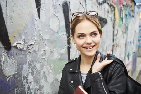 Счастливая женщина читает книгу на улице рядом с граффити на стене