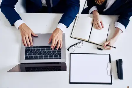 Менеджеры работают с ноутбуком и документами на столе, используя технологии