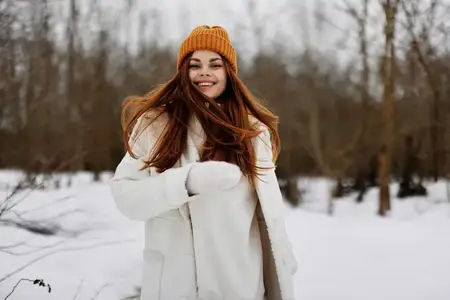 Молодая женщина в зимней одежде и шапке, веселая зимняя атмосфера, образ жизни
