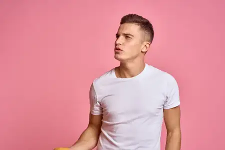 Мужчина с фруктами в руках на розовом фоне