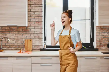 Домохозяйка жестикулирует руками на кухне в квартире, среди кухонной утвари и предметов интерьера