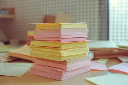 Стопка разноцветных стикеров на столе перед открытым окном, отражающая темы путешествий и деловой продуктивности